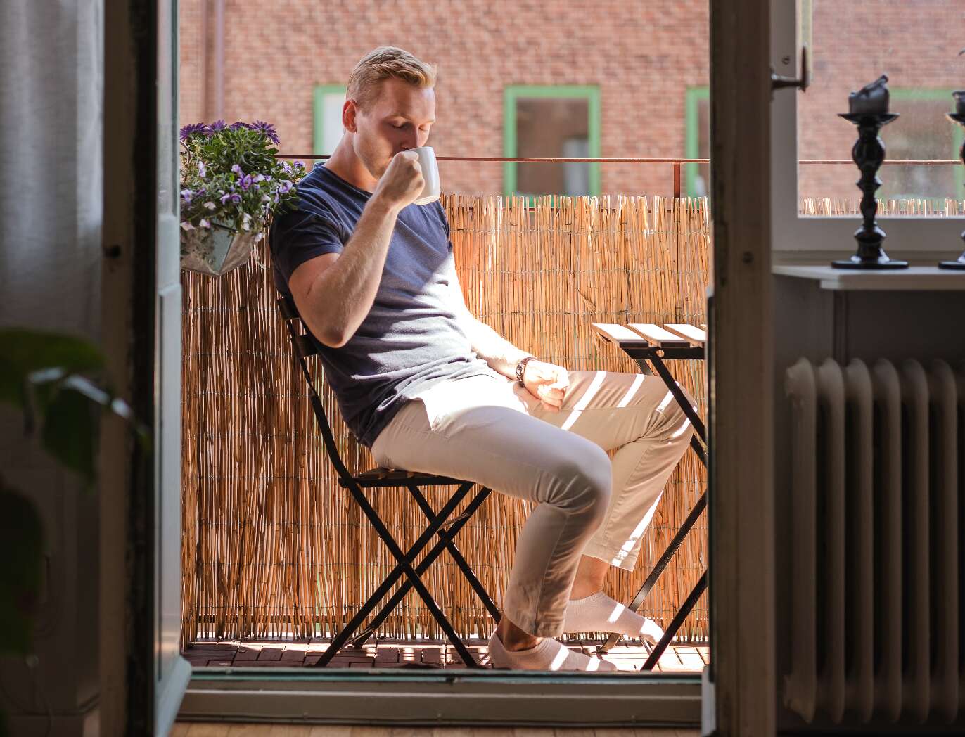 En man sitter på en balkong och dricker kaffe