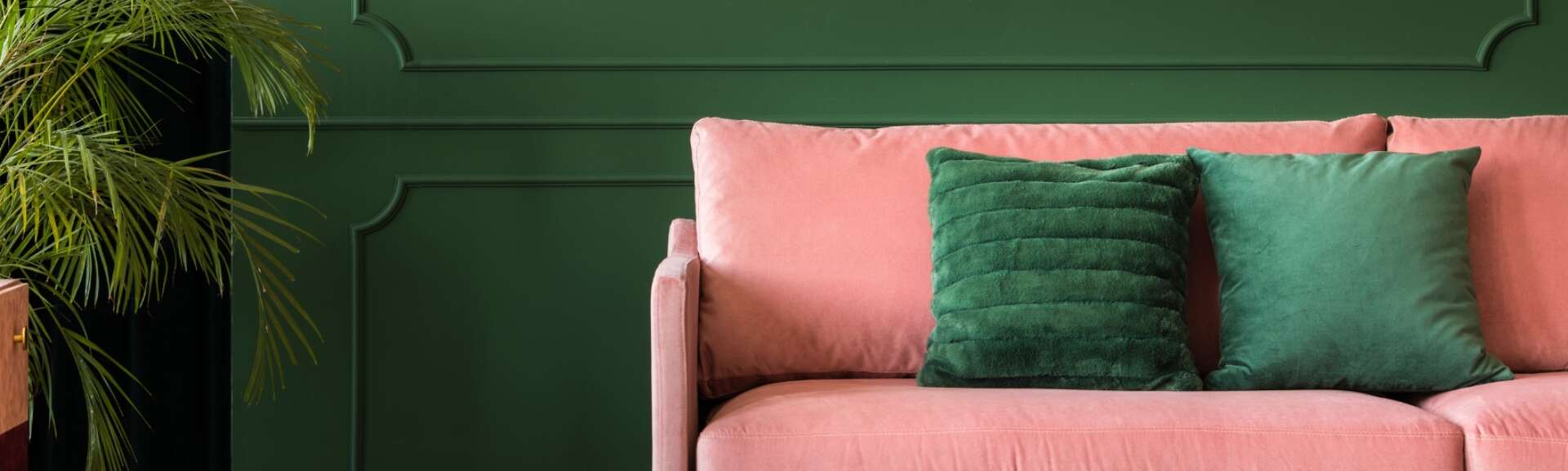 En rosa soffa i ett grönmålat rum